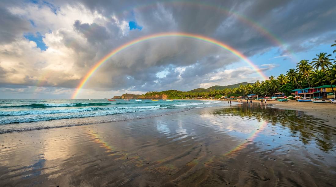 Stunning rainbow arcing over Goa beach after monsoon rain shower - magical rainy season
